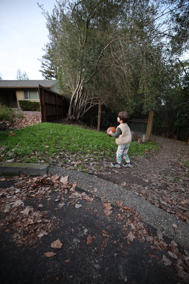Young Child with Football on Suburban Street at Dusk