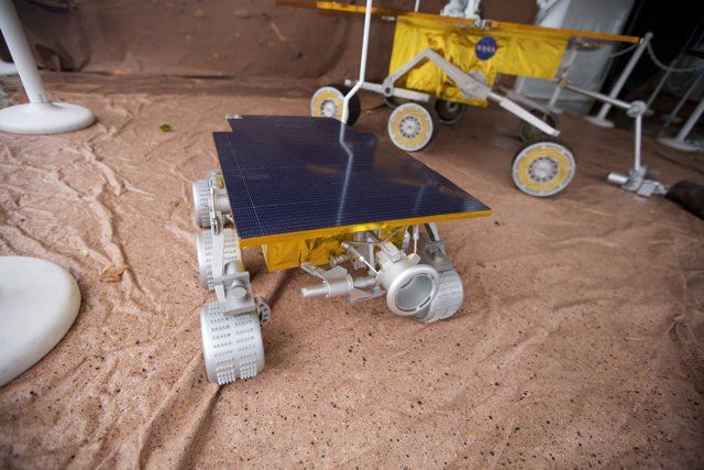 Model Rover with White Object on Plywood Ground