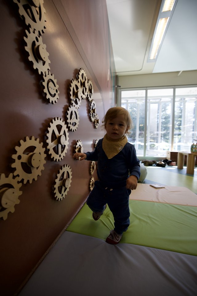 Toddler Playing on Interactive Gear Wall Installation