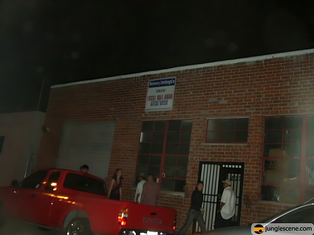 Red Pickup Truck Parked Outside Brick Building at Night