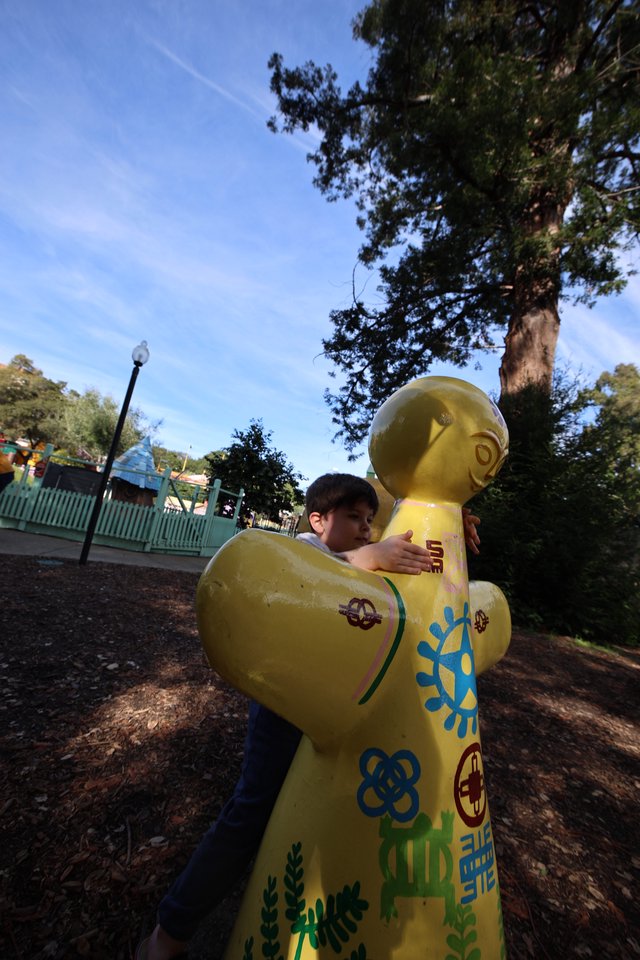 Child Hugging Large Yellow LEGO Figure at Theme Park