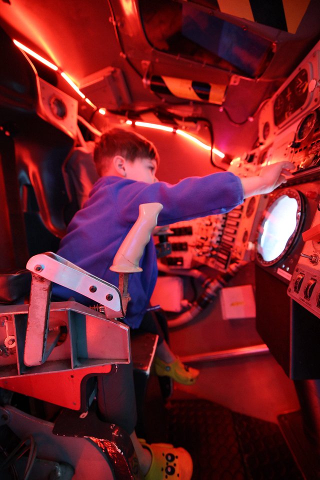 Young Astronaut Training in Red-Lit Space Capsule Simulator