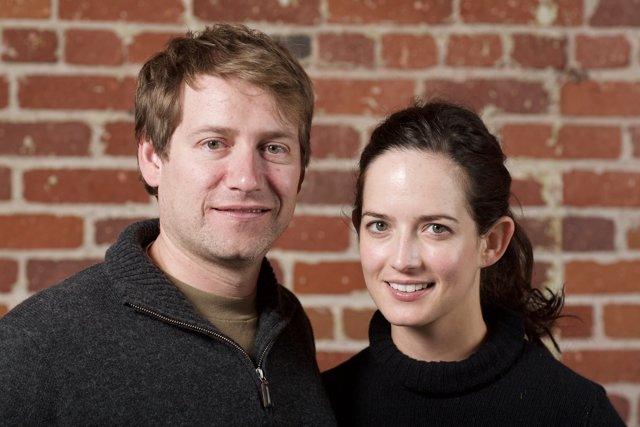 Smiling Couple Poses in Front of Brick Wall