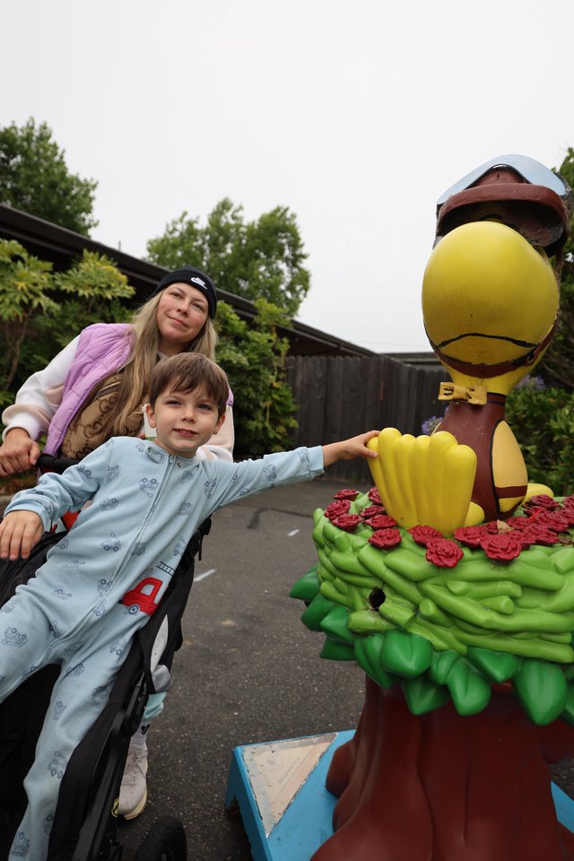 Boy Touches Colorful Bird Statue at Balloon Festival