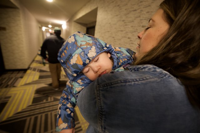 Sleeping Child Carried Through Hotel Hallway at Night