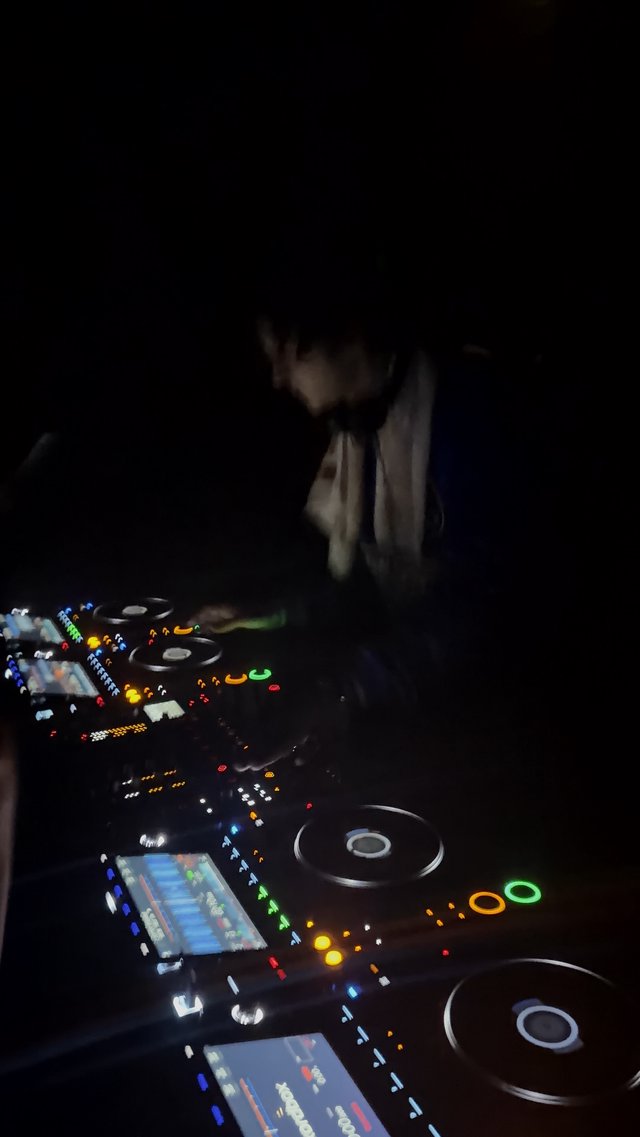 DJ Performing in Dark Nightclub with Illuminated Equipment