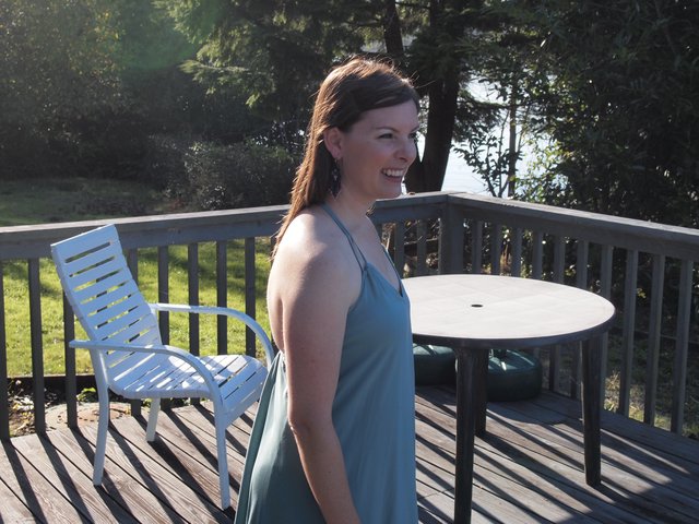 Woman in Teal Dress Smiling on Sunny Deck