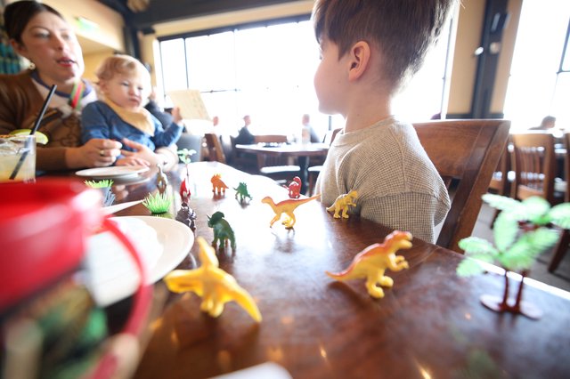 Family Dinosaur Play Time at Restaurant Table