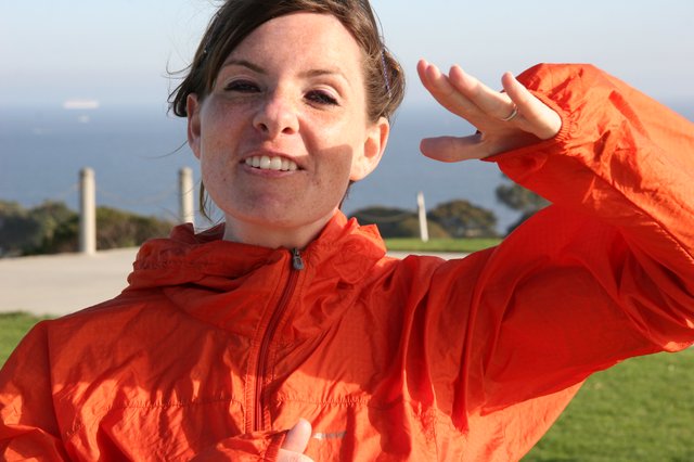 Radiant Woman in Orange Jacket by the Sea