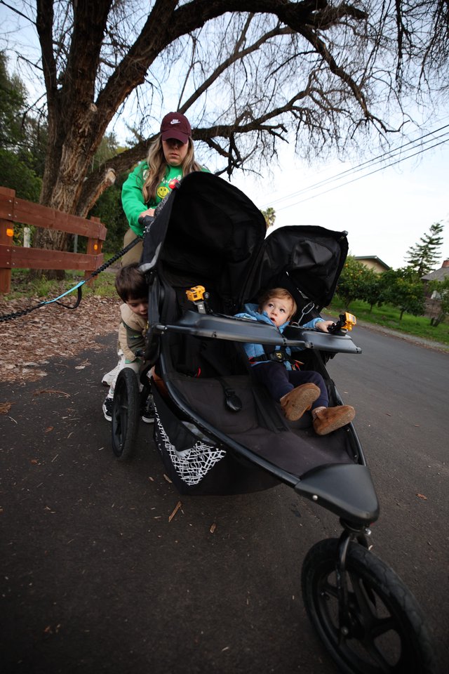 Mother with Two Children in Double Stroller on Suburban Walk