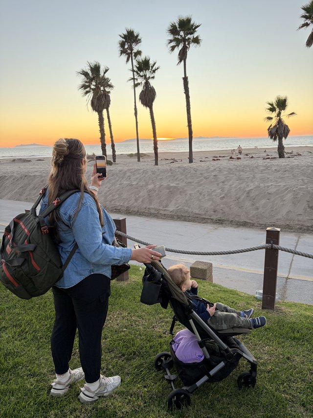 Mother Capturing Sunset Beach Moment with Child