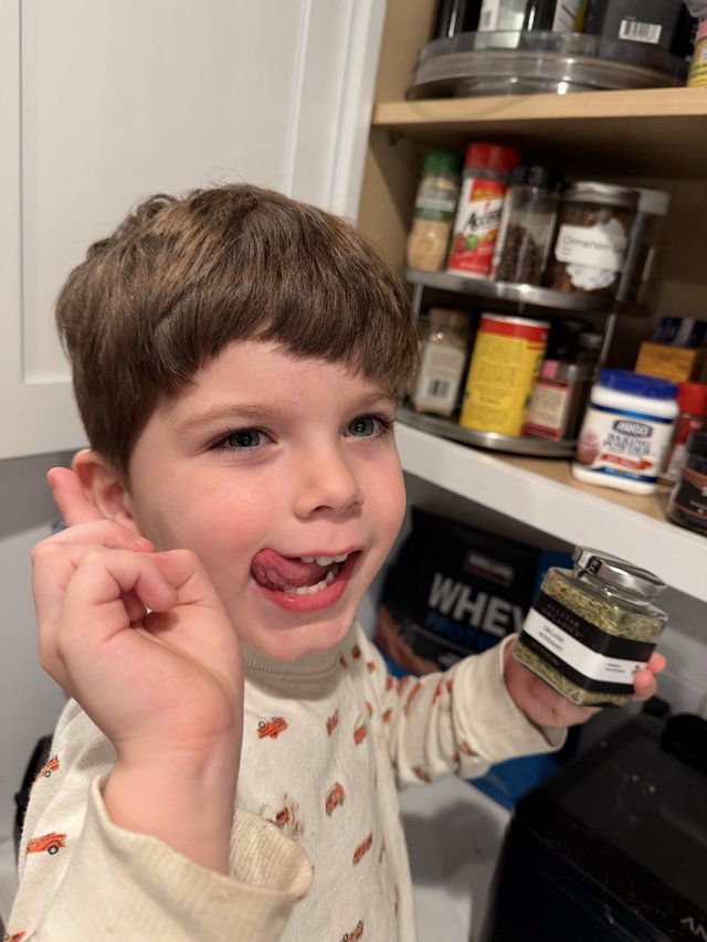 Young Boy Enjoying Spices in Kitchen