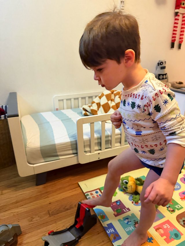 Young Boy Playing in Festive Pajamas on Bedroom Floor