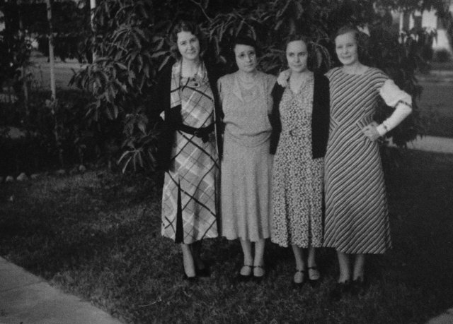 Four women in beautiful dresses posing for a photo