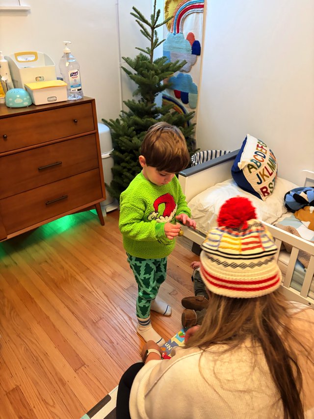 Young Child Examining Art or Toy by Christmas Tree