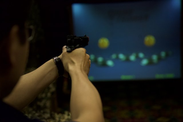 Man Holding Pistol in Front of Screen
