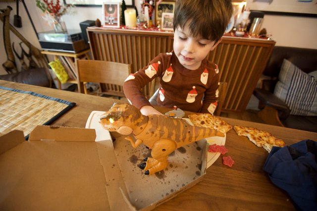 Child Delighting in Dinosaur-Shaped Christmas Pizza