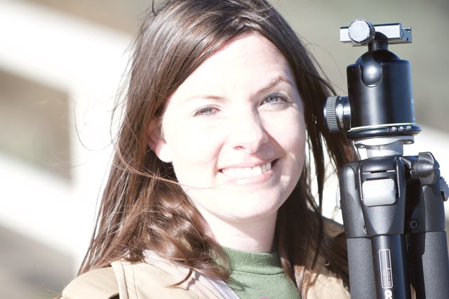 Smiling Photographer Holding Tripod in Bright Sunlight
