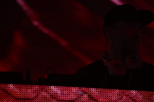 Silhouetted DJ Performing Under Crimson Stage Lights