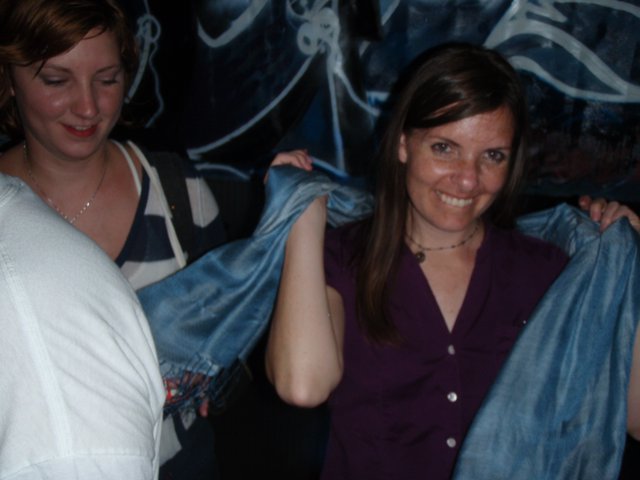 Two Women Holding Blue Fabric at Nighttime Event