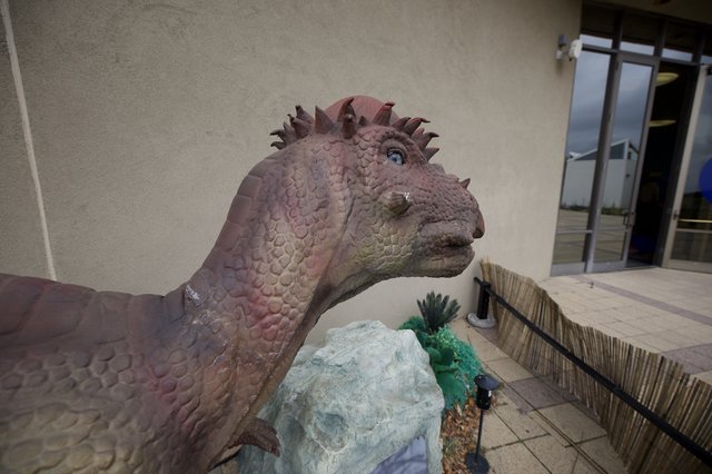 Whimsical Dinosaur Statue at Modern Building Entrance