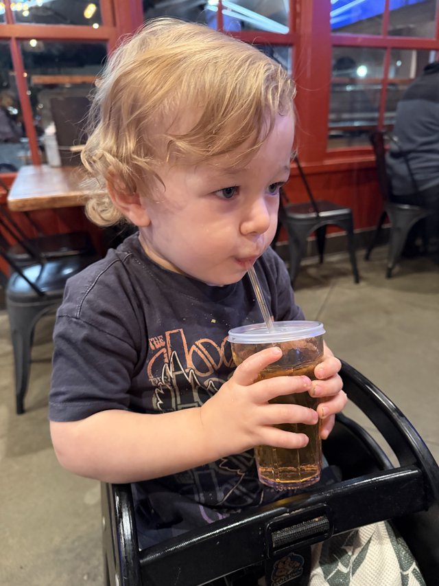Toddler Enjoying a Drink at Local Restaurant