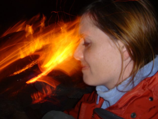 Woman Gazing Into Campfire on Dark Night