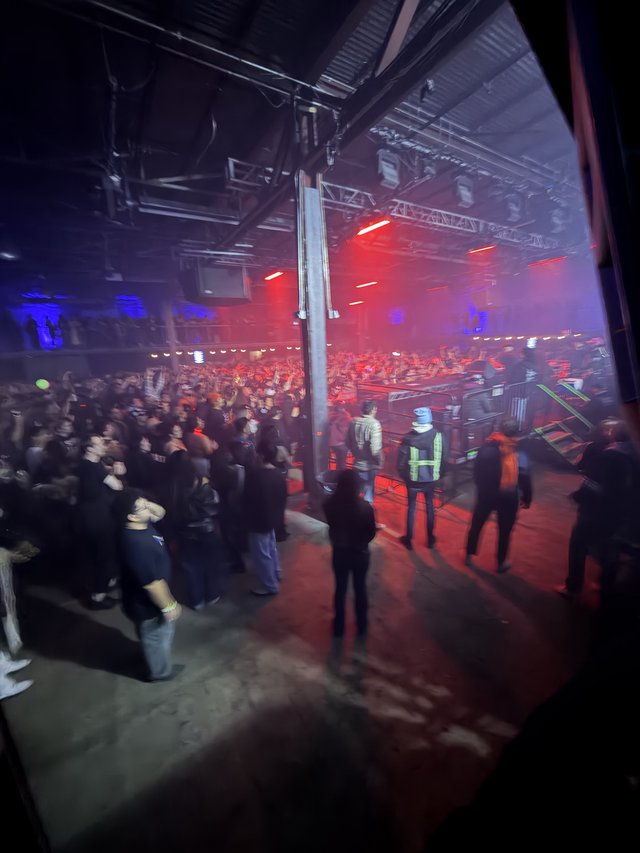 Red-Lit Industrial Warehouse Concert with Crowd and Security