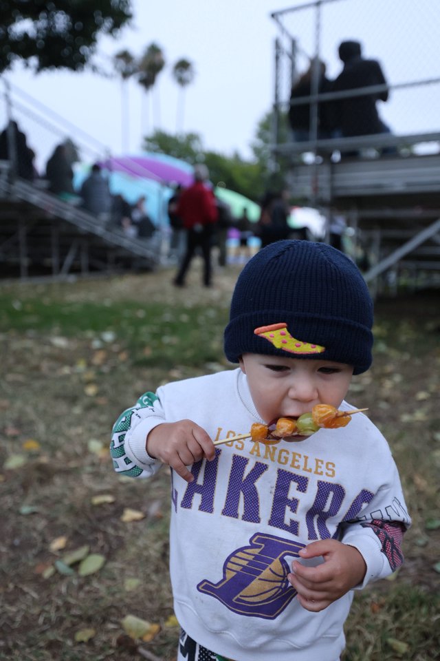 Young Lakers Fan Enjoying Skewered Treats at Festival