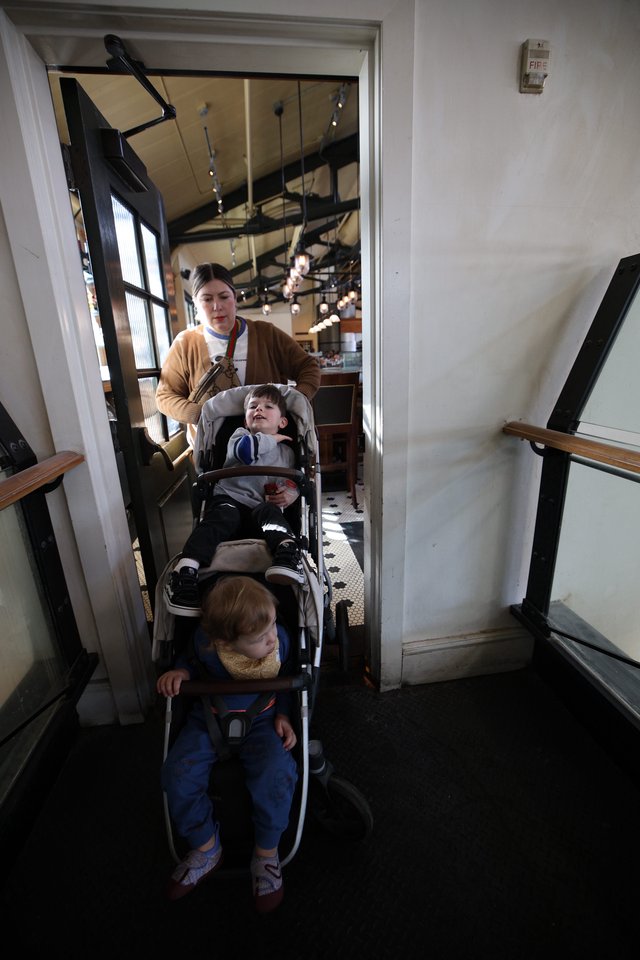Parent Navigating Narrow Restaurant Stairwell with Double Stroller