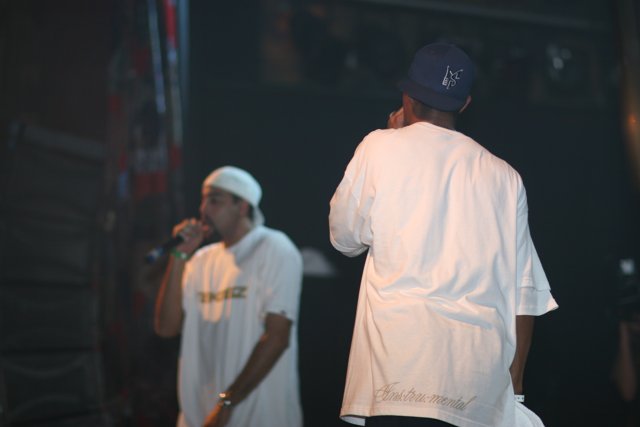 Two Men Perform on Stage with Baseball Caps