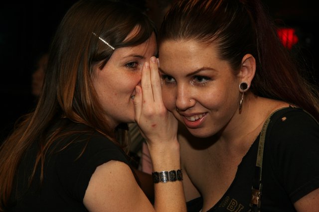 Two Friends Sharing a Secret at a Nightclub