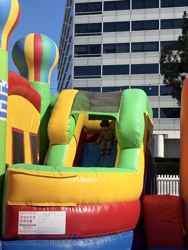Child on Inflatable Bounce House Slide in Urban Setting