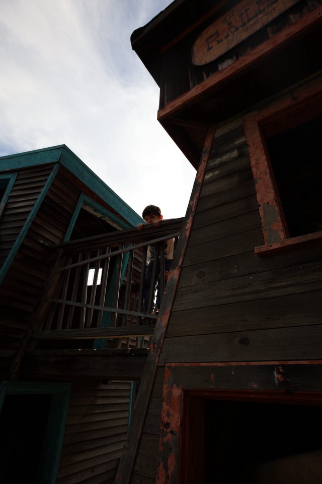 Child Peering from Weathered Wooden Balcony at Dusk