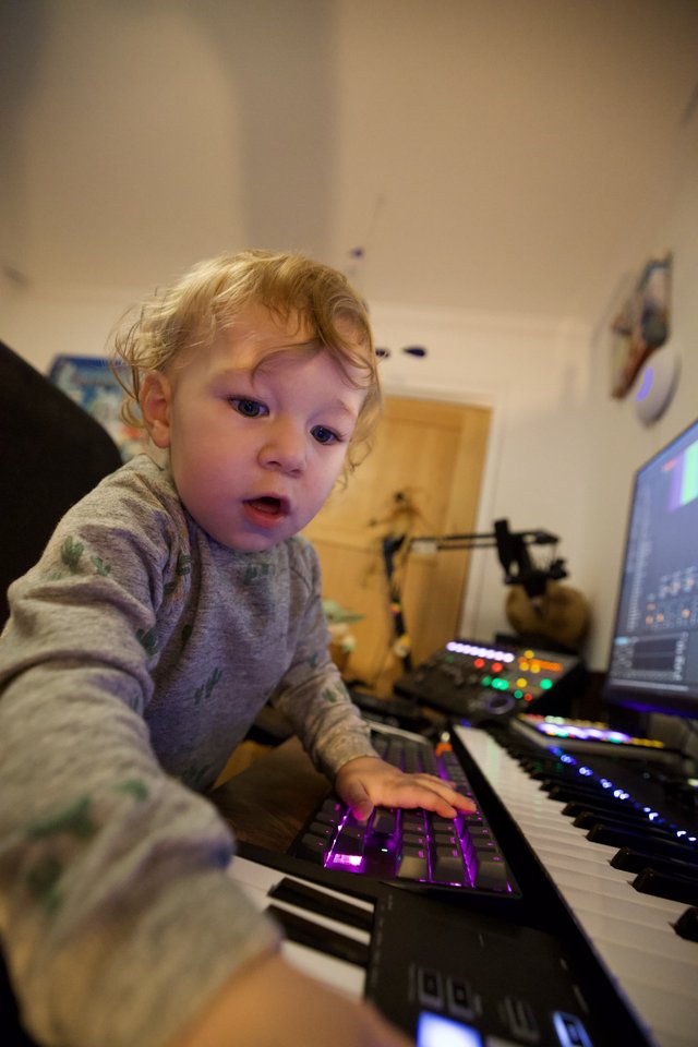 Young Child Exploring Music Production Equipment at Night