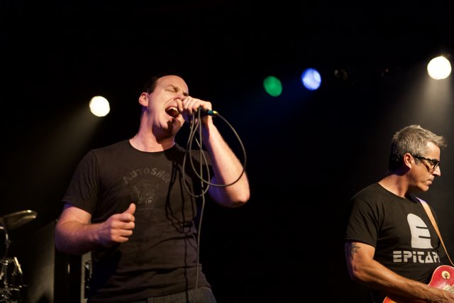 Two Men on Stage Singing with Microphones