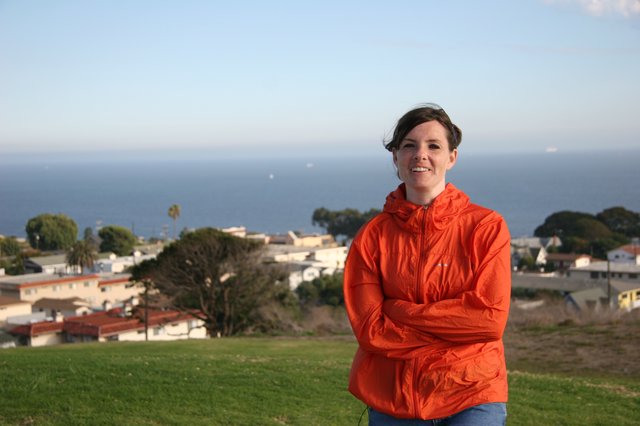 Woman in Orange Jacket Overlooking Coastal Town