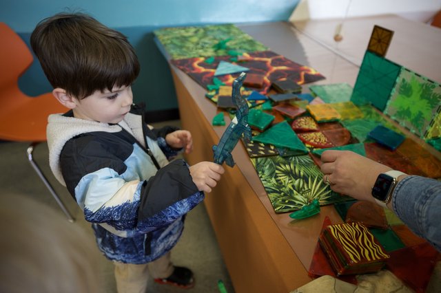 Young Child Explores Dinosaur Toy at Interactive Play Table