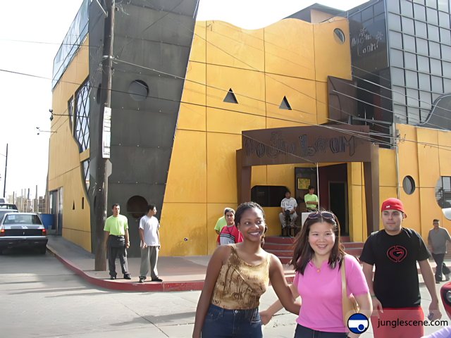 Three People Pose in Front of Yellow Ensenada Building