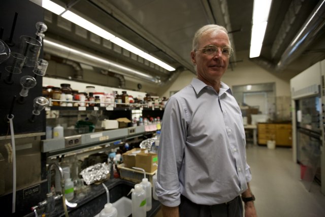 Lab Coat Man Examines Shelf of Nanomachines