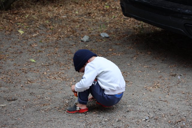 Young Boy Explores the Ground at Campsite