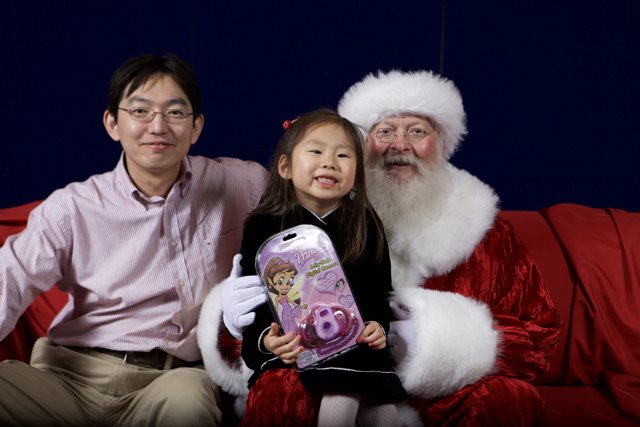 Santa Claus joins a little girl and her friend for the APC Christmas party