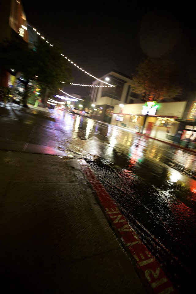 Rain-Slicked City Street at Night with String Lights