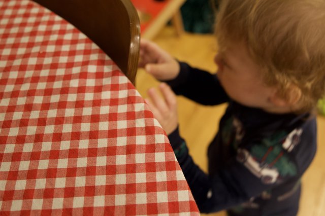 Young Child Reaching for Red Checkered Chair Cushion