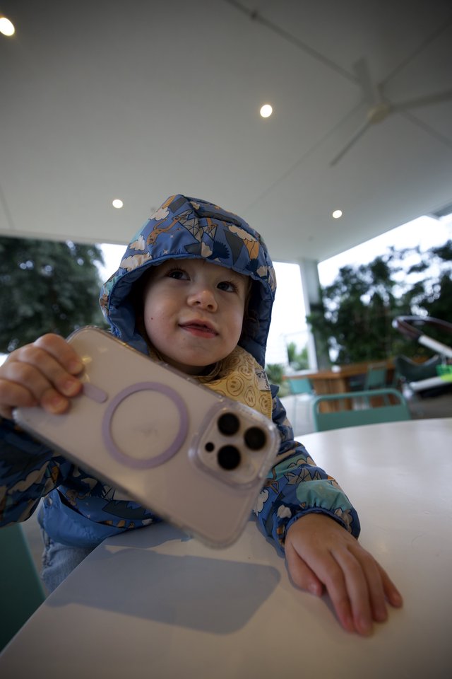 Toddler with Phone at Outdoor Dining Venue