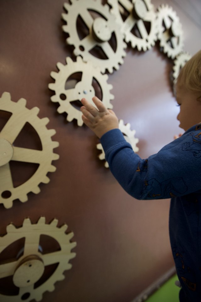 Child Exploring Interactive Gear Wall at Museum