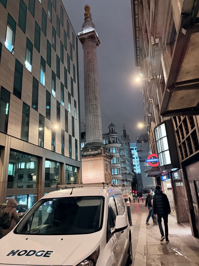 Monument Column Towers Over Modern London Street at Night