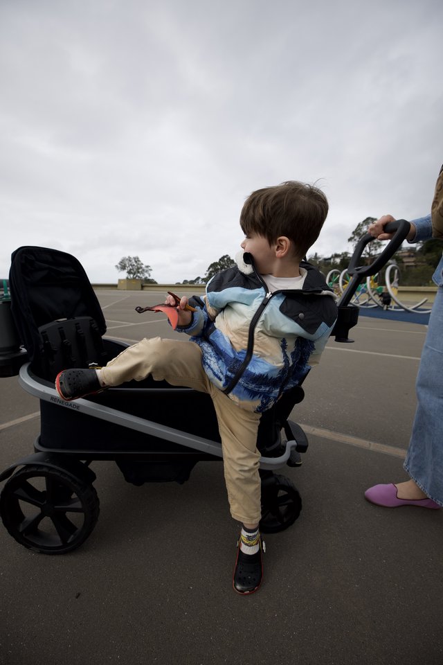 Young Boy Helping Push Stroller in Parking Lot