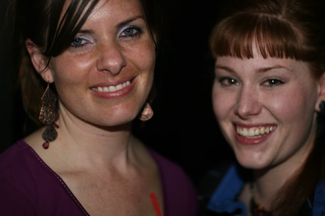 Two Smiling Women at a Nighttime Social Gathering