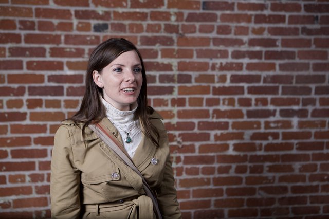 Woman in Trench Coat Against Rustic Brick Wall